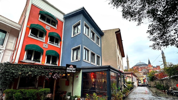 Un hôtel avec une enseigne indiquant « MODERN Sultan Hotel », situé dans une rue pavée.