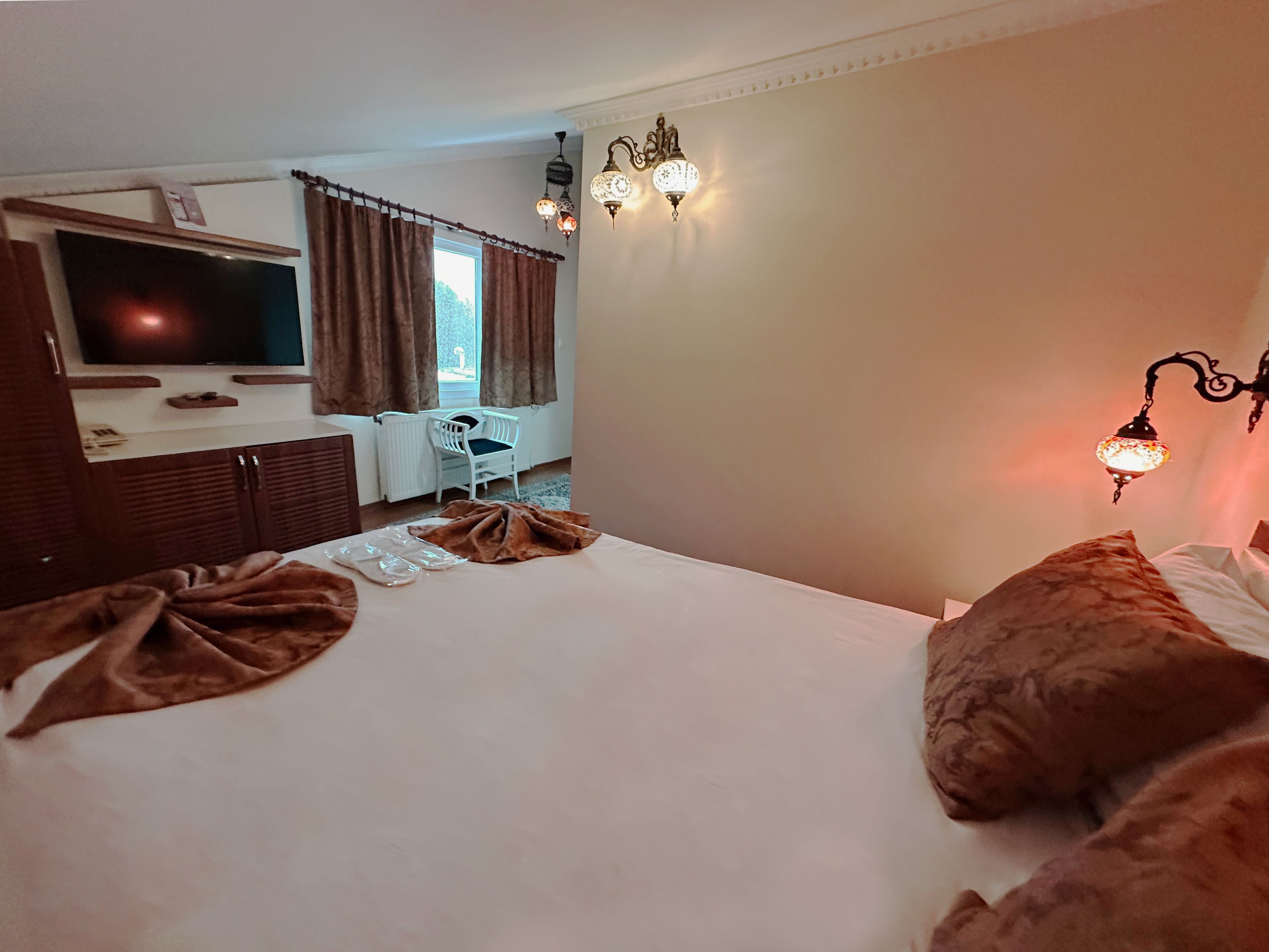 Habitació d'hotel amb un llit, televisió, escriptori i cadira.