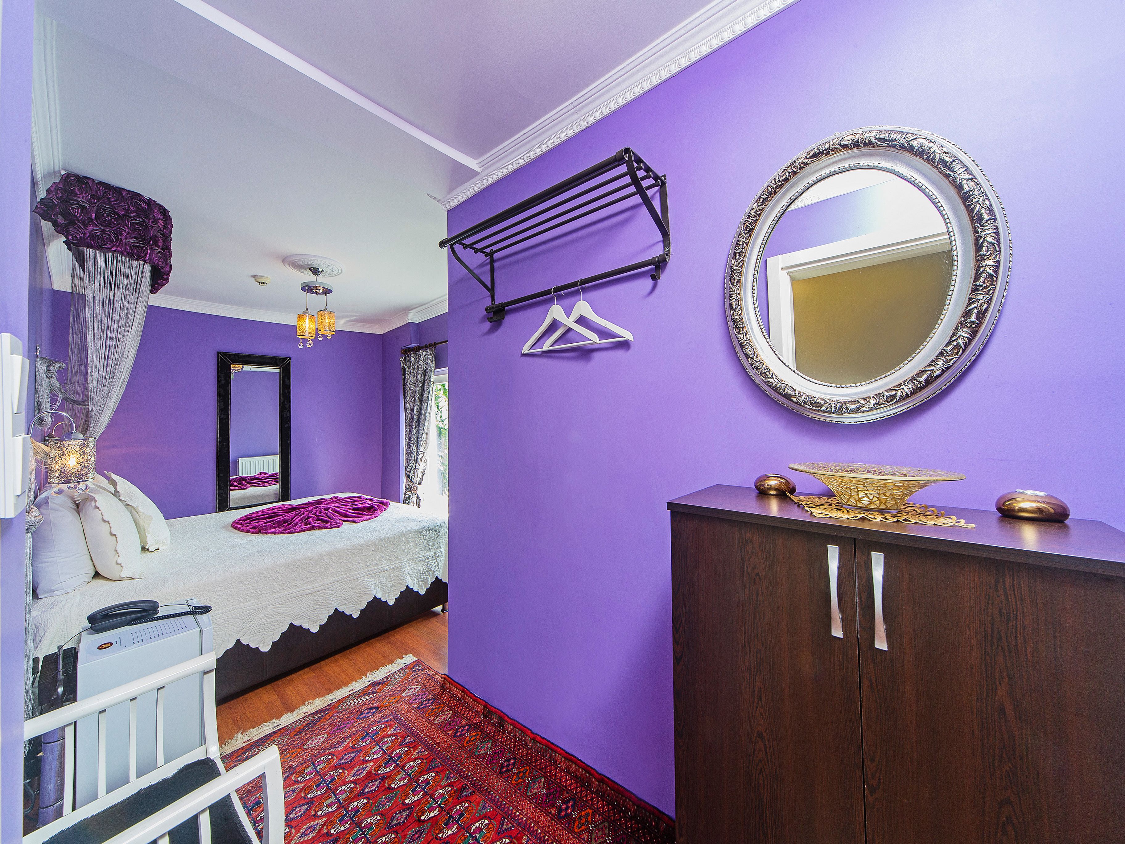 Une chambre à coucher comprenant un lit, une armoire, un miroir et un porte-vêtements.