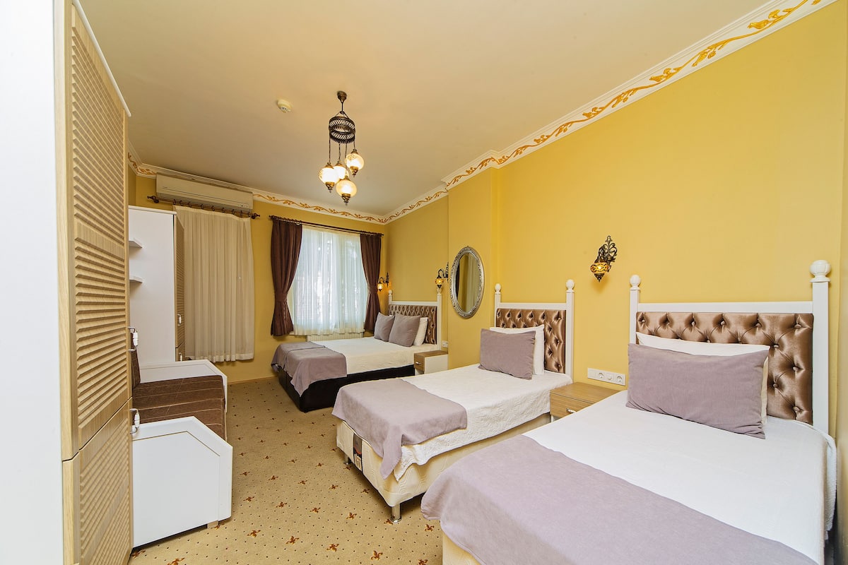 Une chambre d’hôtel avec deux lits, une armoire, un miroir et un luminaire au plafond.