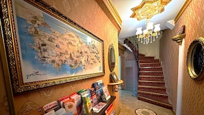 Un couloir avec une carte, un miroir, un escalier et un présentoir rempli de brochures de voyage.