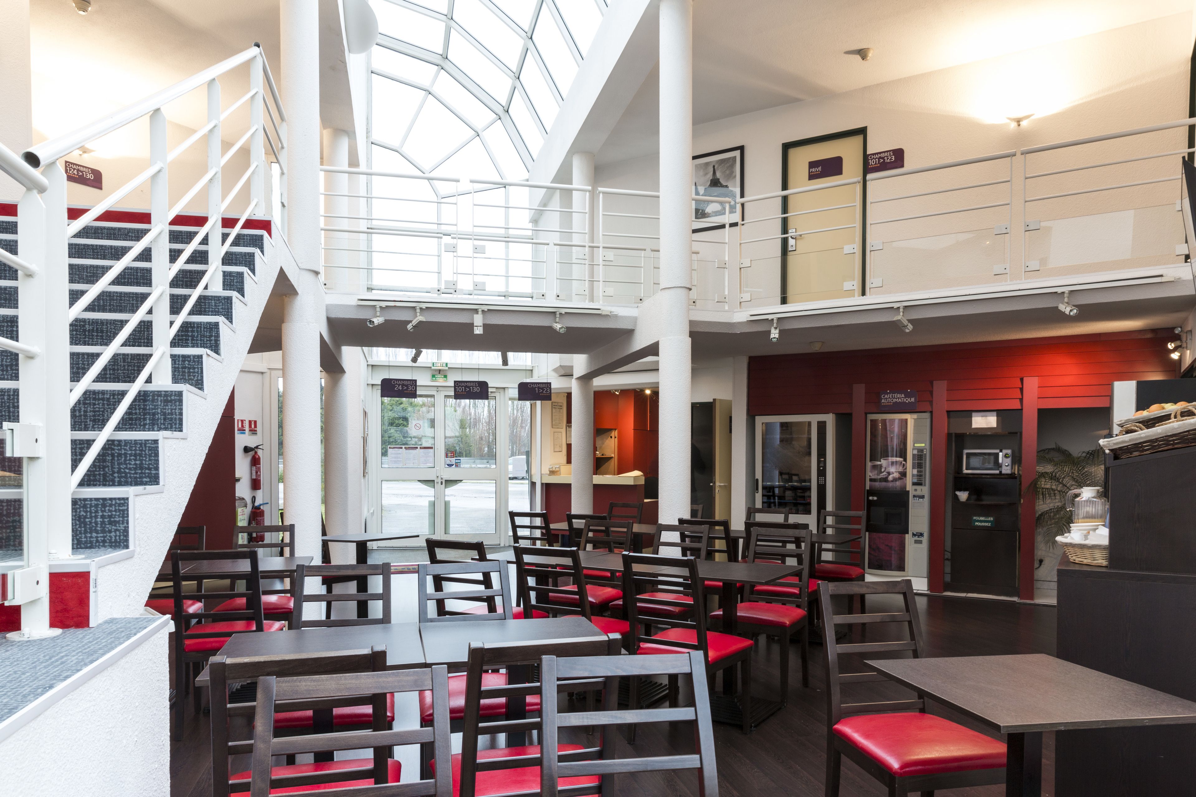 A spacious indoor area with multiple seating arrangements, a staircase, and a mezzanine level.