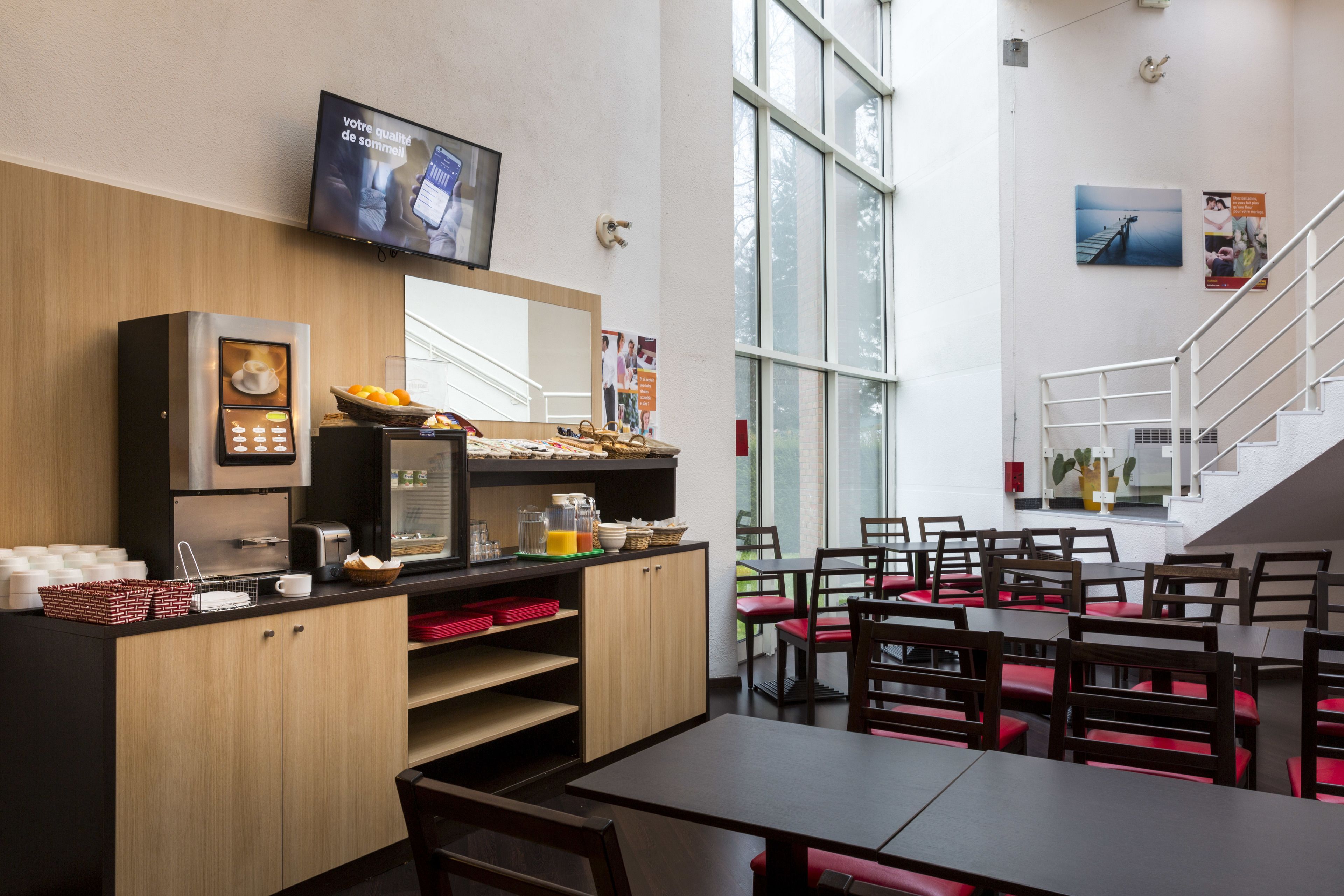 Een modern café met een balie, een zithoek en een trap.