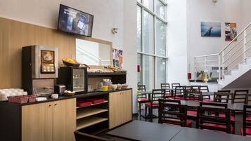 Een modern café met een balie, een zithoek en een trap.