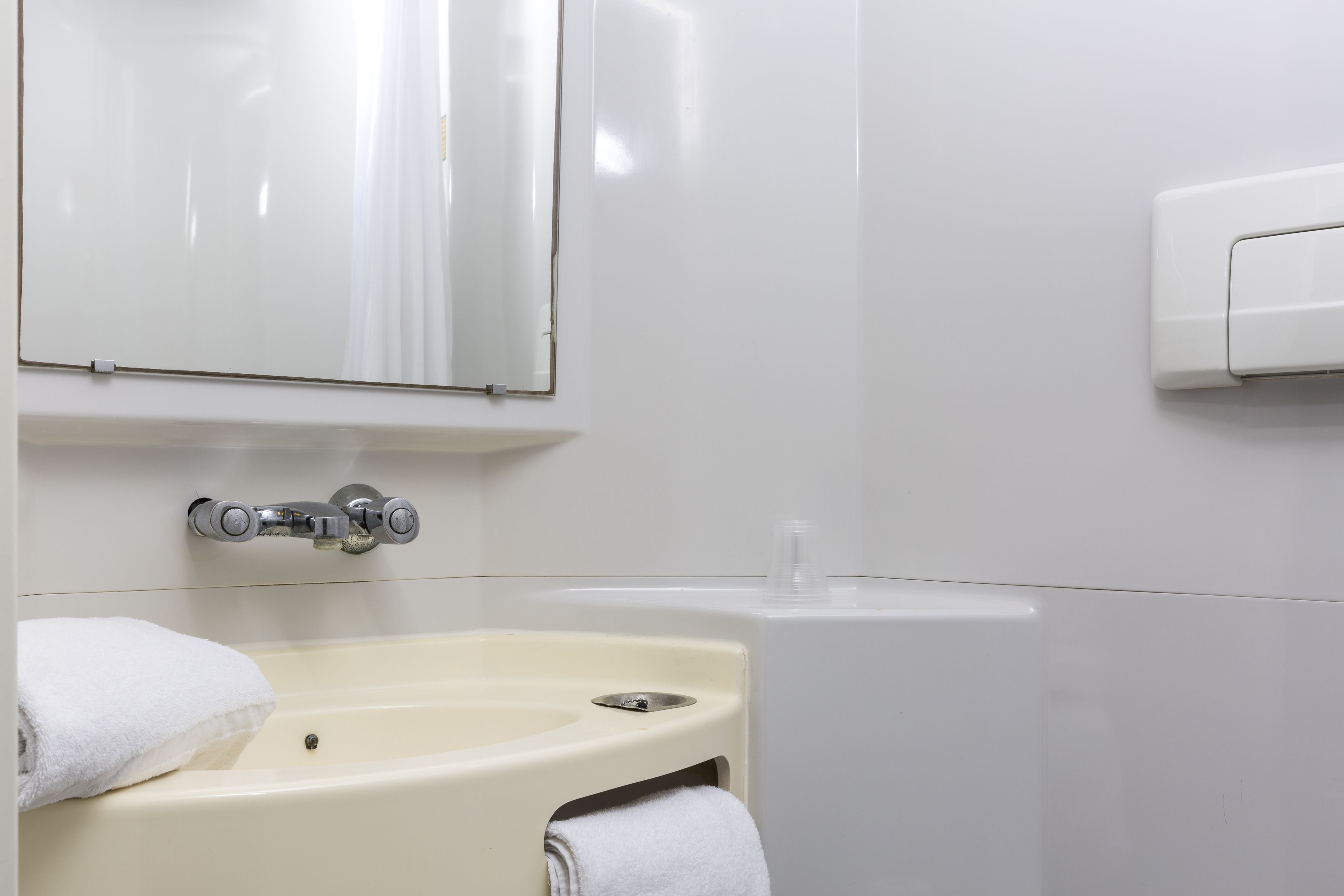 Een badkamer met een wit wastafelmeubel, een spiegel en een handdroger.