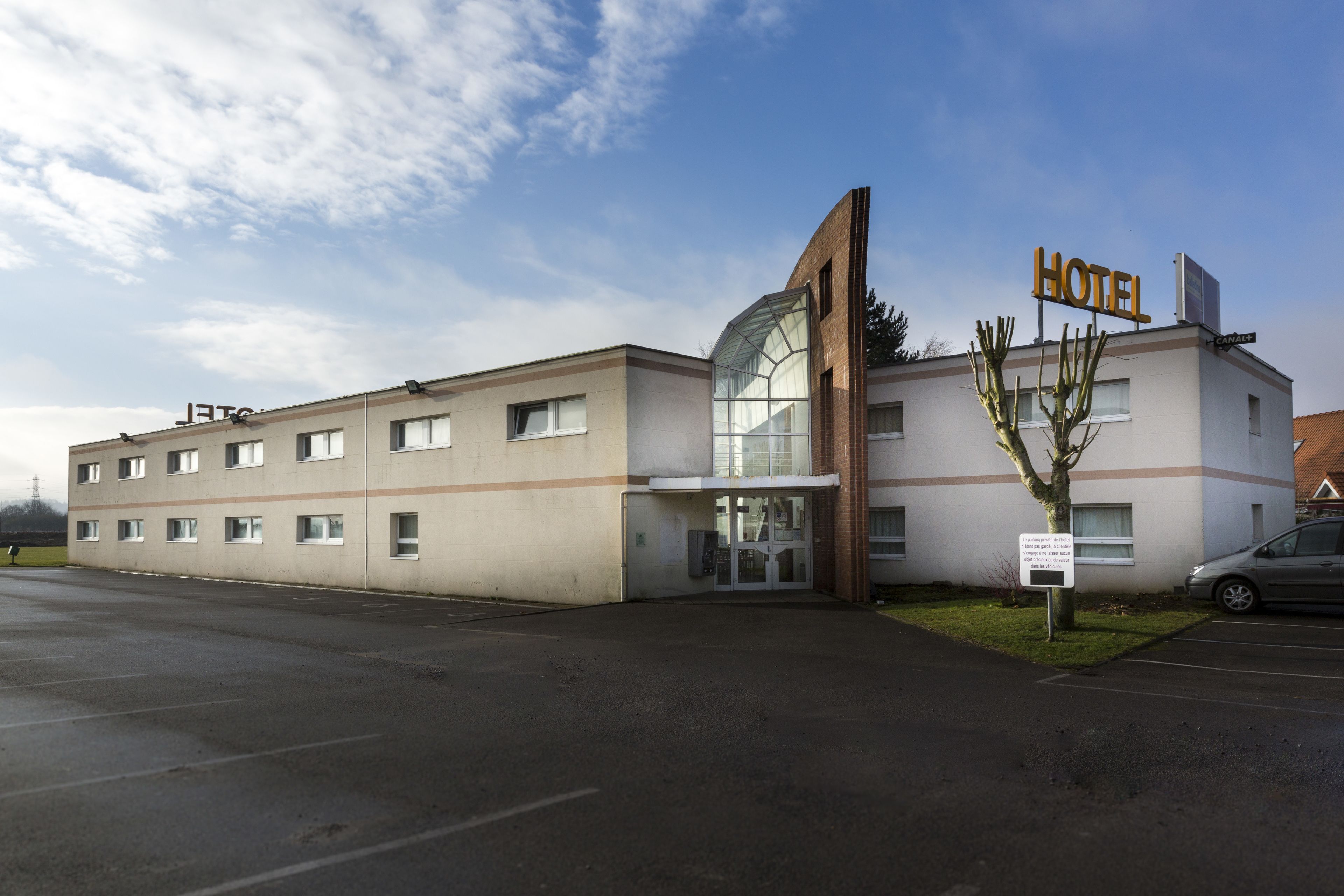 A hotel with a modern design, featuring a large glass entrance and a prominent 'HOTEL' sign.