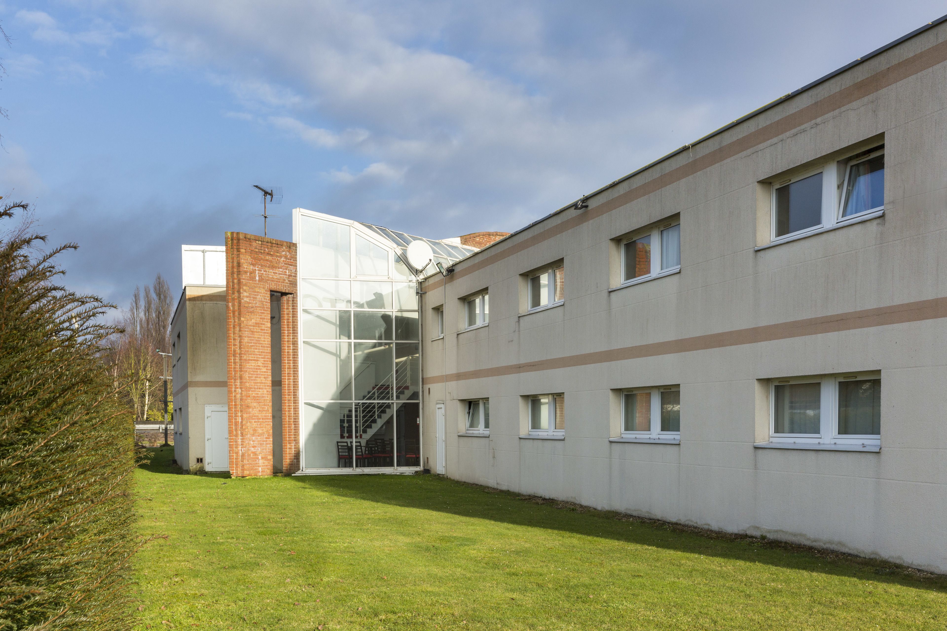 Un edificio moderno con entrada de vidrio, sección de ladrillo y varias ventanas.