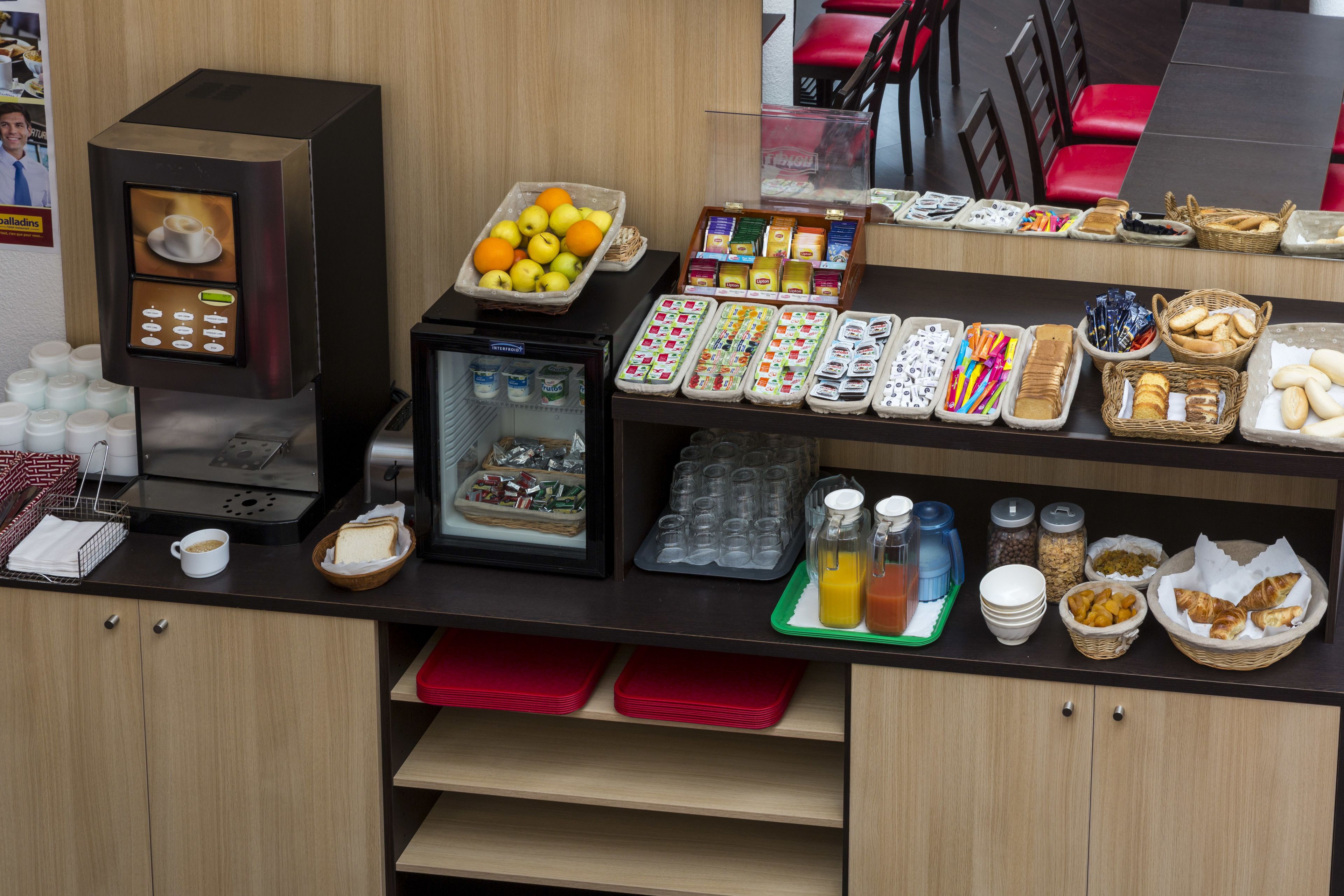 Ein Frühstücksbuffet mit verschiedenen Speisen, einer Kaffeemaschine und einem Kühlschrank.