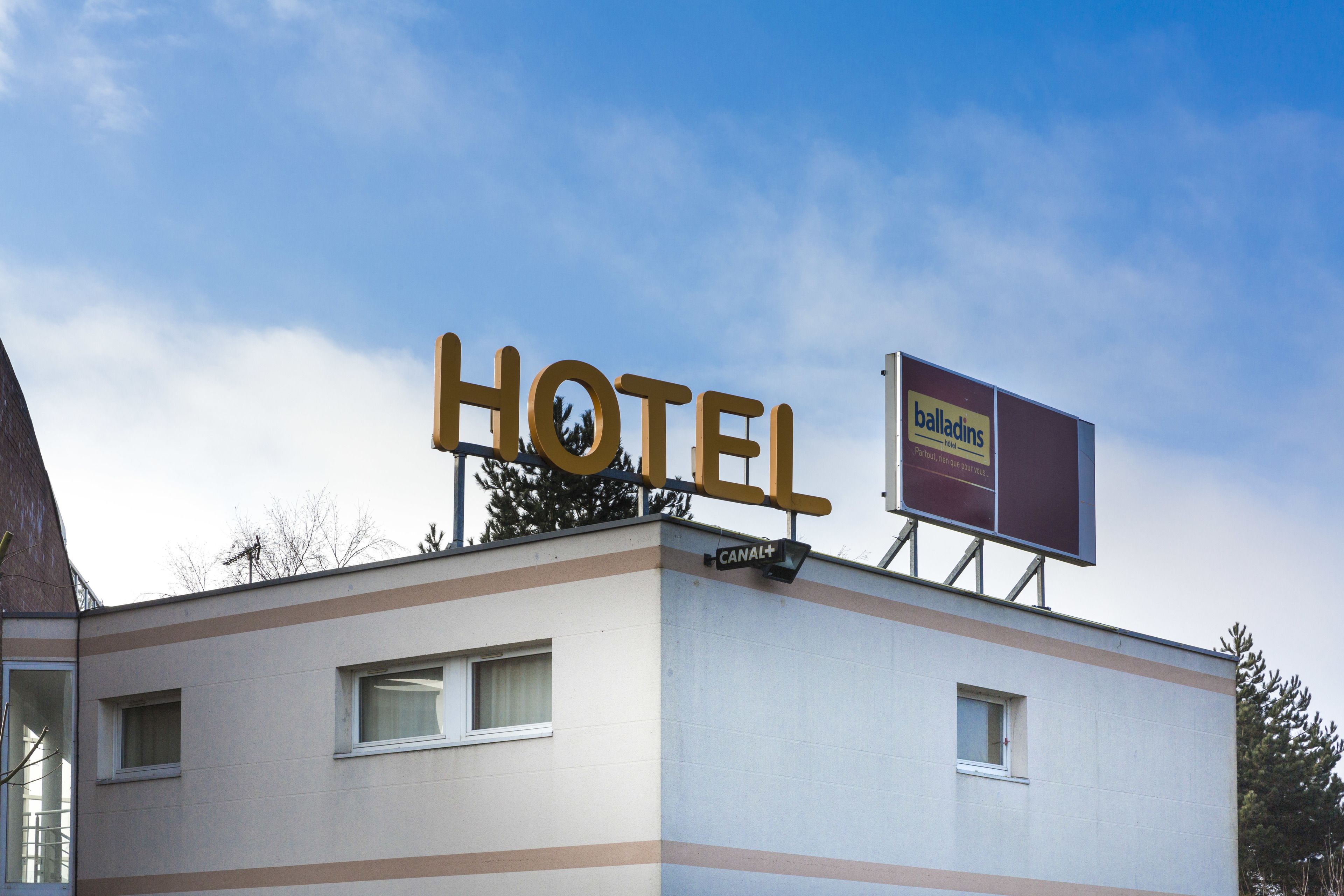 A hotel building with a prominent 'HOTEL' sign and a 'balladins' billboard.