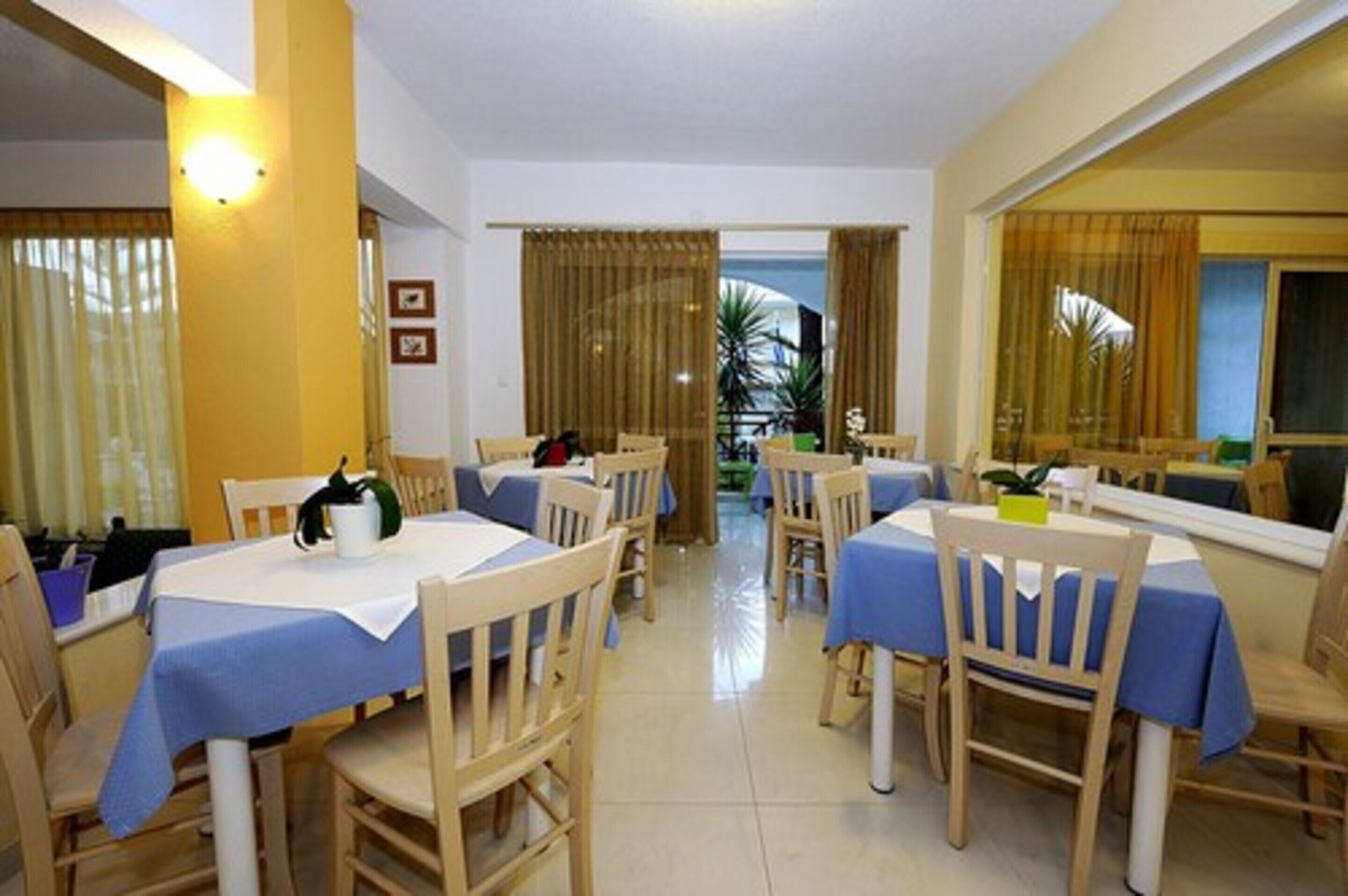A dining area with tables covered in blue tablecloths and wooden chairs.