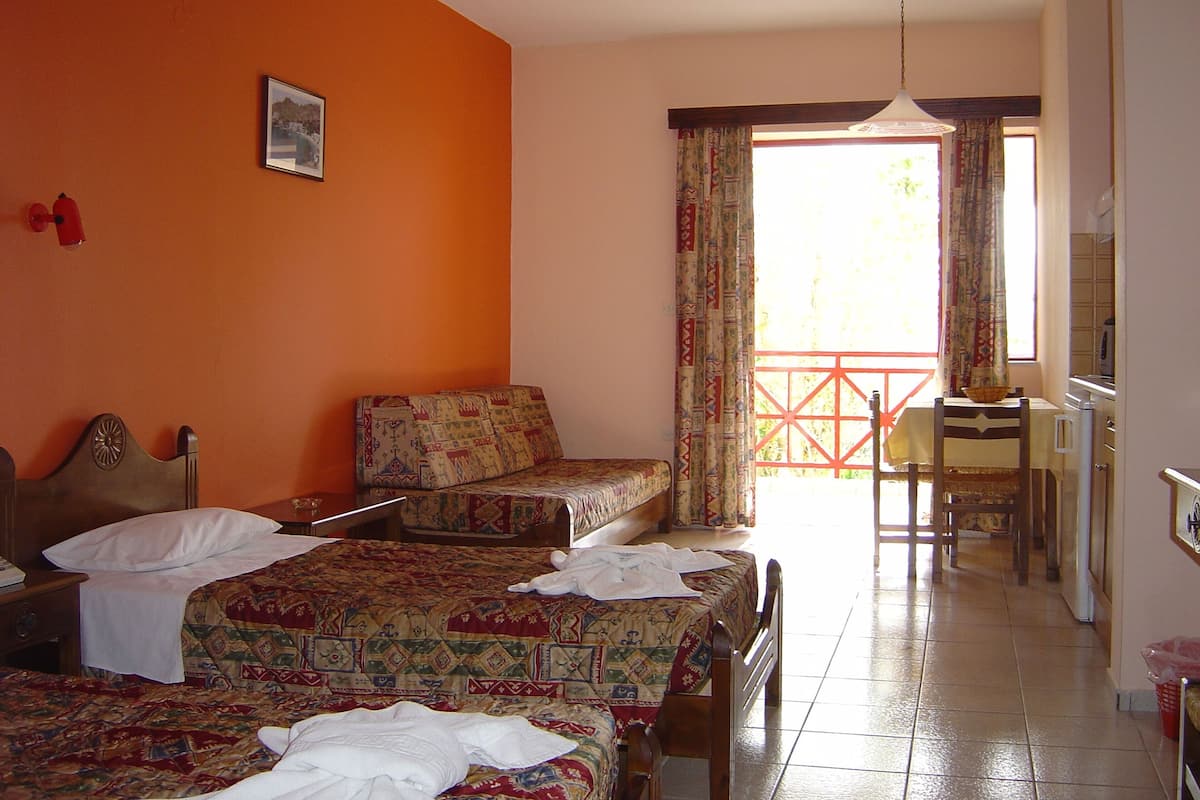 Una habitación de hotel con dos camas, una zona de comedor y vistas al exterior.