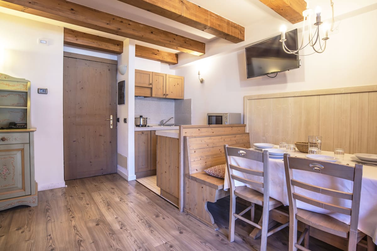 A kitchen with wooden cabinets, a microwave, and a dining area with a table and chairs.