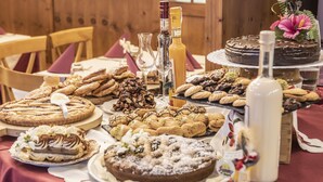 A table with various desserts and beverages, including cakes, pastries, and bottles. - Al Sole Clubresidence (Canazei)