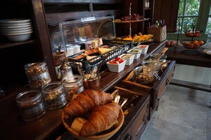 Ein Buffet mit verschiedenen Speisen, darunter Croissants, Früchte und Beilagen.