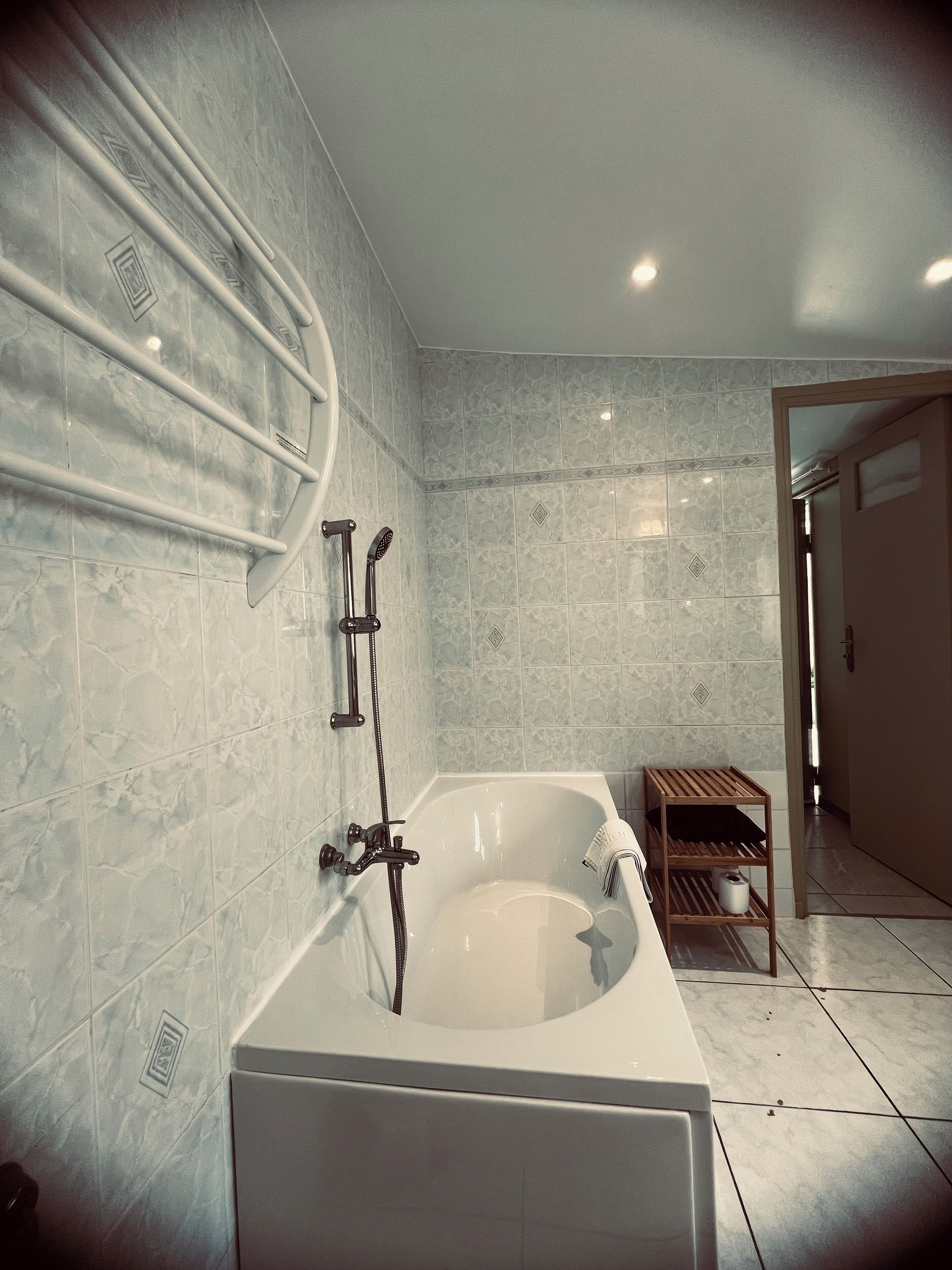 A modern bathroom with a freestanding bathtub, a showerhead, and a towel rack.