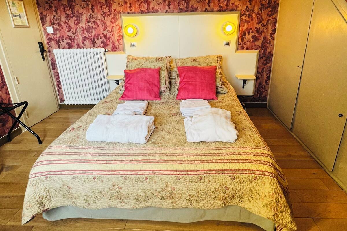 Ein Schlafzimmer mit einem Bett, zwei Nachttischlampen, einem Heizkörper und einer Tür.