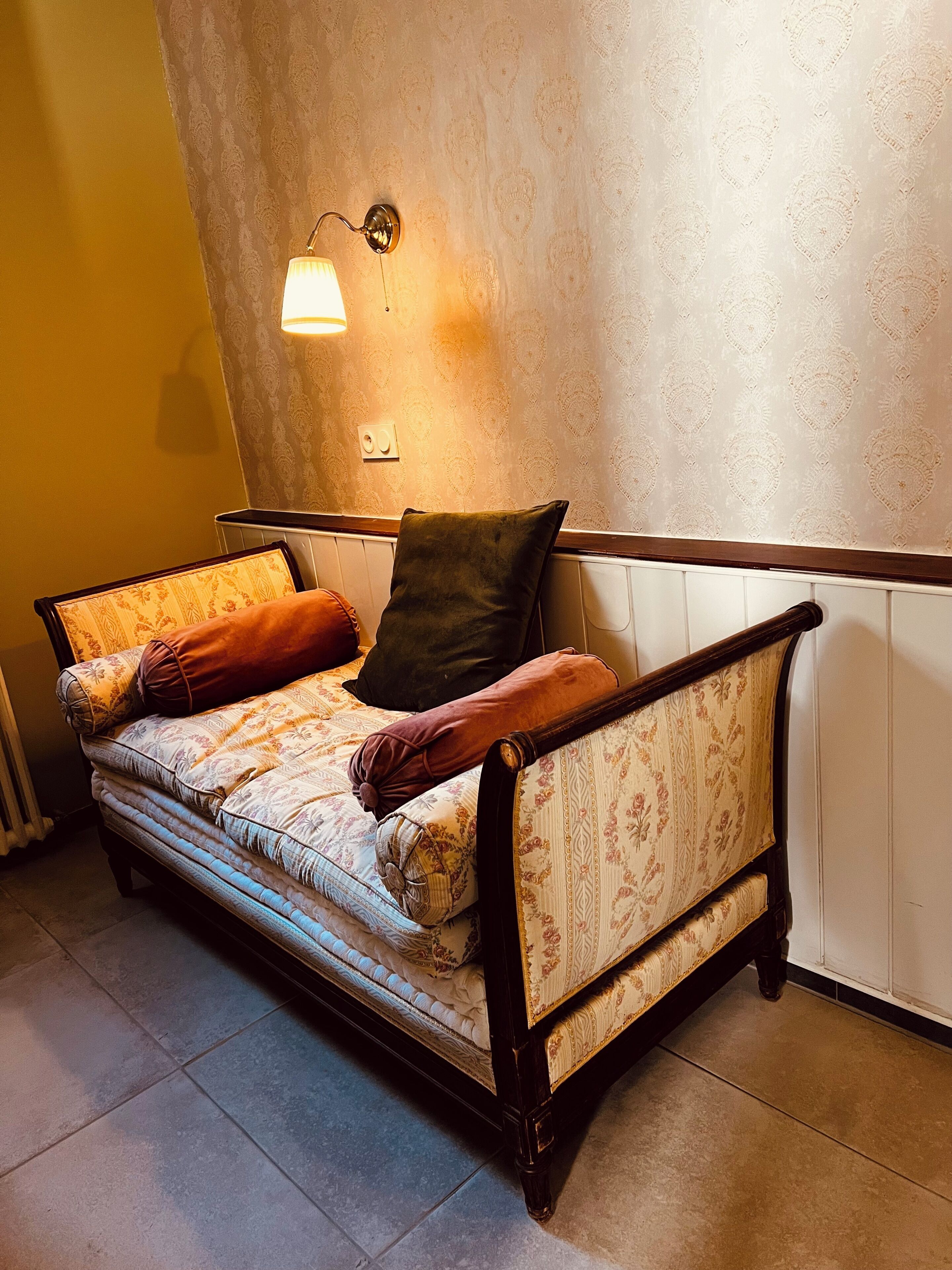 A sofa with patterned cushions and a wall-mounted light fixture.