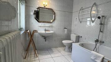 Een moderne badkamer met een bad, toilet en wastafel.