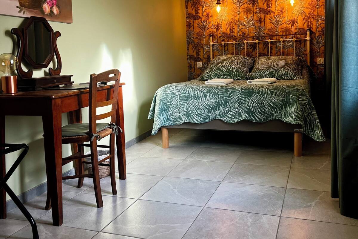 Ein Schlafzimmer mit einem Bett, einem Schreibtisch, einem Stuhl, einer Klimaanlage und einer Wand mit einem Blumenbild.