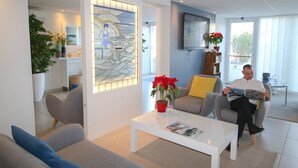 Un salon moderne avec une table basse blanche, un canapé avec des coussins bleus et une plante en pot.