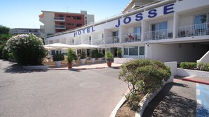 Un hôtel appelé «Hôtel Josse», doté d’un design moderne, avec des balcons, des plantes en pot et une vue sur un ciel dégagé.