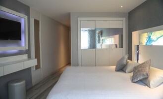 Una camera da letto moderna con un letto grande, una TV a muro e un armadio con specchio.
