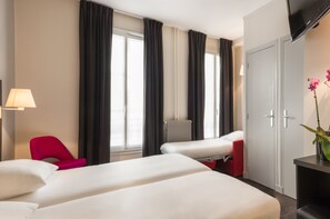 A hotel room with two beds, a red chair, a desk with a lamp, and a wardrobe. - Hôtel des Ecrivains (Paris)