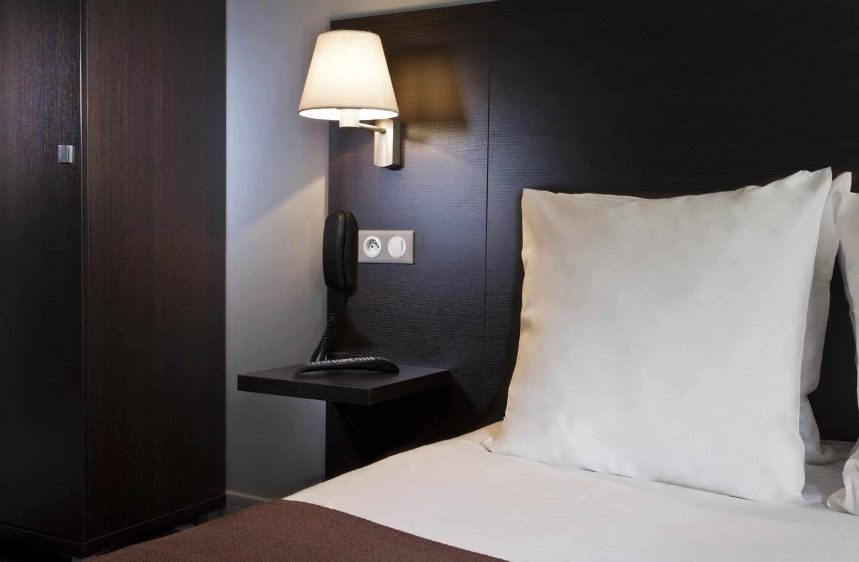 Une chambre d’hôtel avec un lit, une table de chevet avec une lampe et un téléphone.