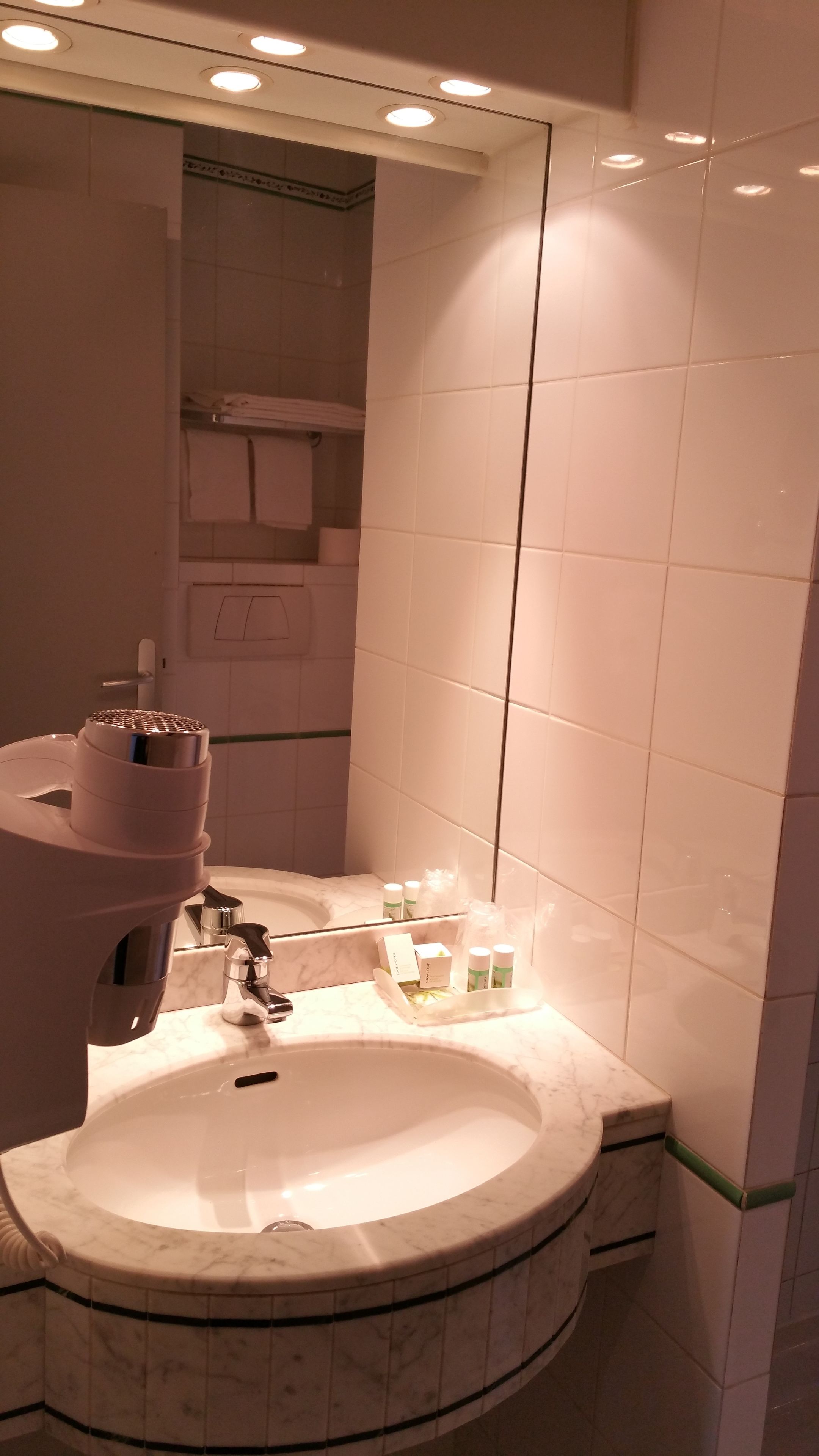 A bathroom with a marble sink, a mirror, and a towel rack.