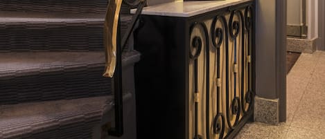 A staircase with ornate black metal railings and a decorative lamp on a console table.