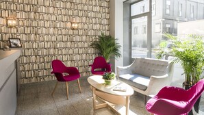 A modern interior with a bookshelf wall, two vibrant chairs, a sofa, and a coffee table. - Hôtel des Ecrivains (Paris)
