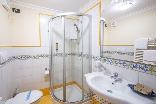 Un baño con cabina de ducha de vidrio, un lavamanos blanco y un inodoro.