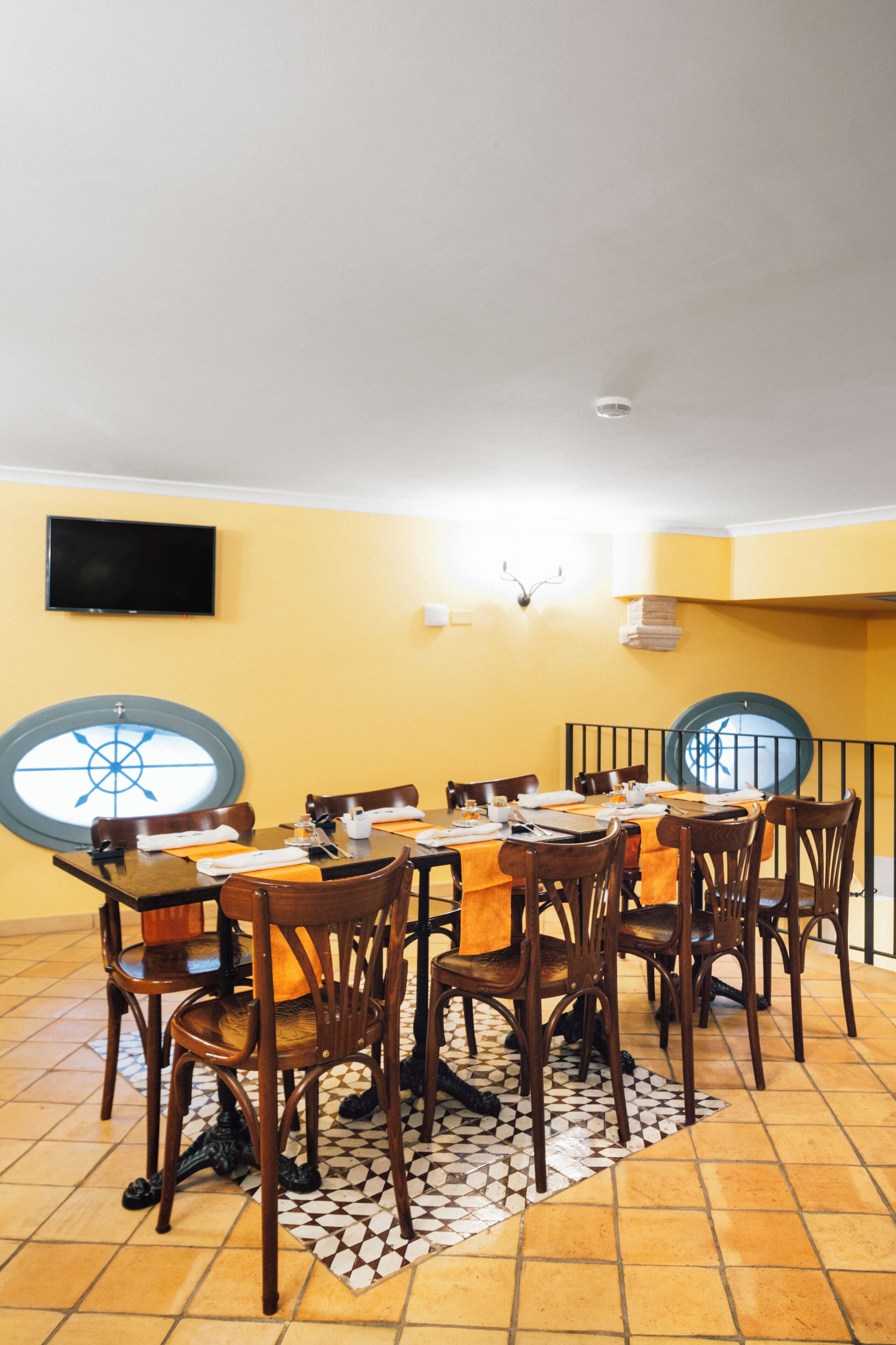 Un comedor con una mesa redonda, sillas y suelo de baldosas.