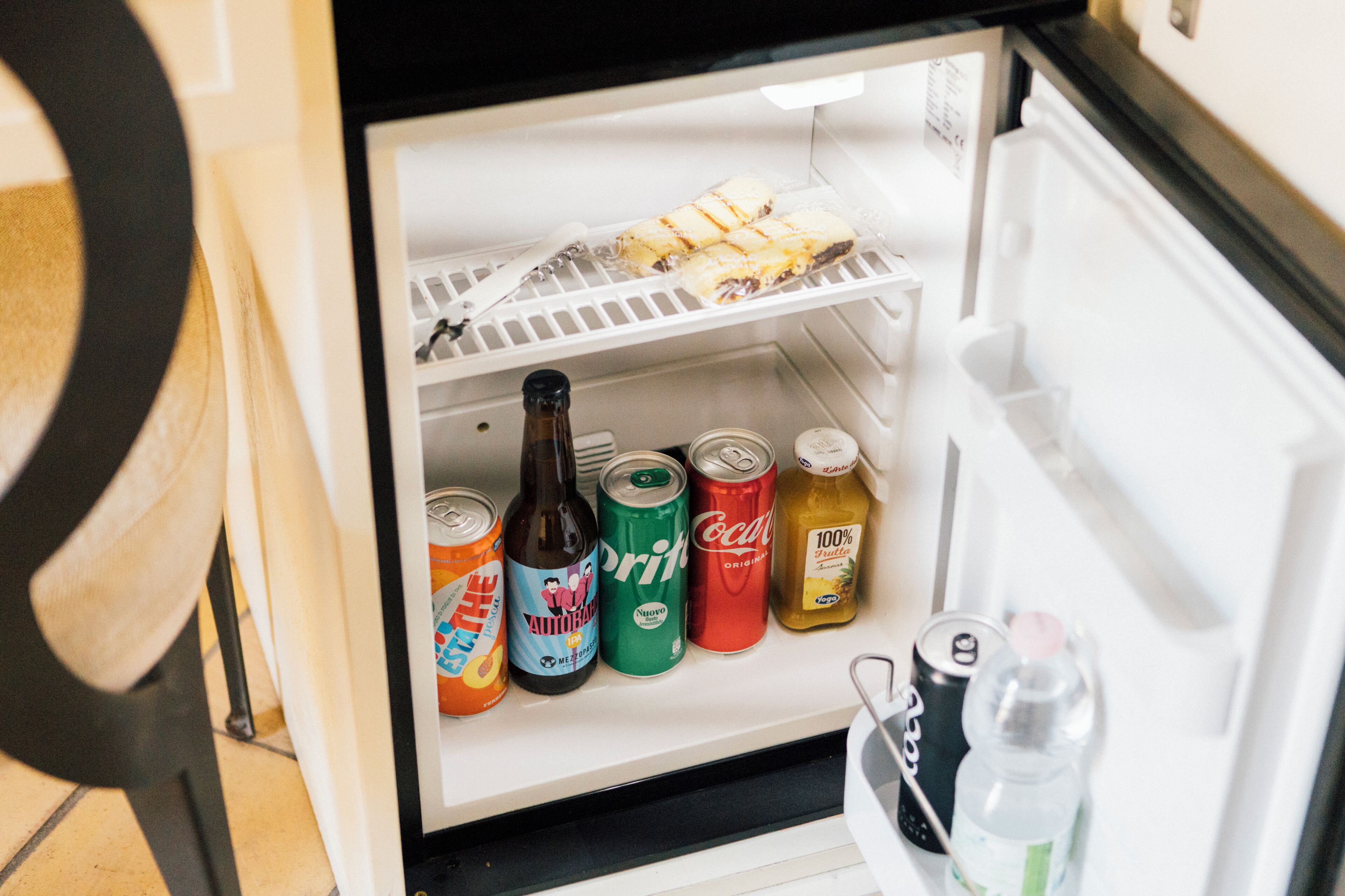 Ein Kühlschrank mit Regalen, die verschiedene Getränke und eine Schale mit Speisen enthalten.