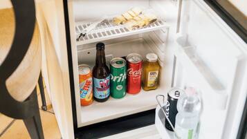 Ein Kühlschrank mit Regalen, die verschiedene Getränke und eine Schale mit Speisen enthalten.
