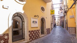 A narrow street with yellow buildings, a sign for 'Il Quartuccio', and a 'Servizio' sign. - Quartuccio - Albergo Diffuso (Gaeta)