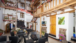 A multi-level wooden interior with a staircase, dining area, and potted plants. - Casona les Pleiades (Cusco)