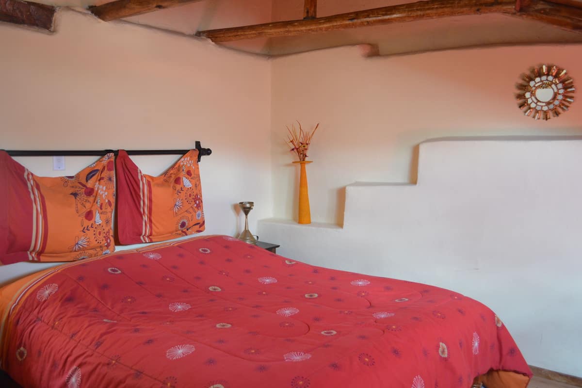 Un dormitorio con una cama, un estante en la pared con un jarrón y un adorno mural.
