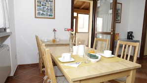 Un coin repas avec une table en bois mise pour le petit-déjeuner, comprenant des tasses, un pichet et un bol.