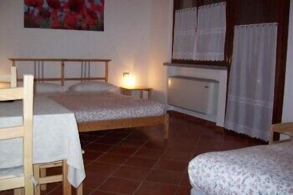 A bedroom with two beds, a wooden table, and a radiator.