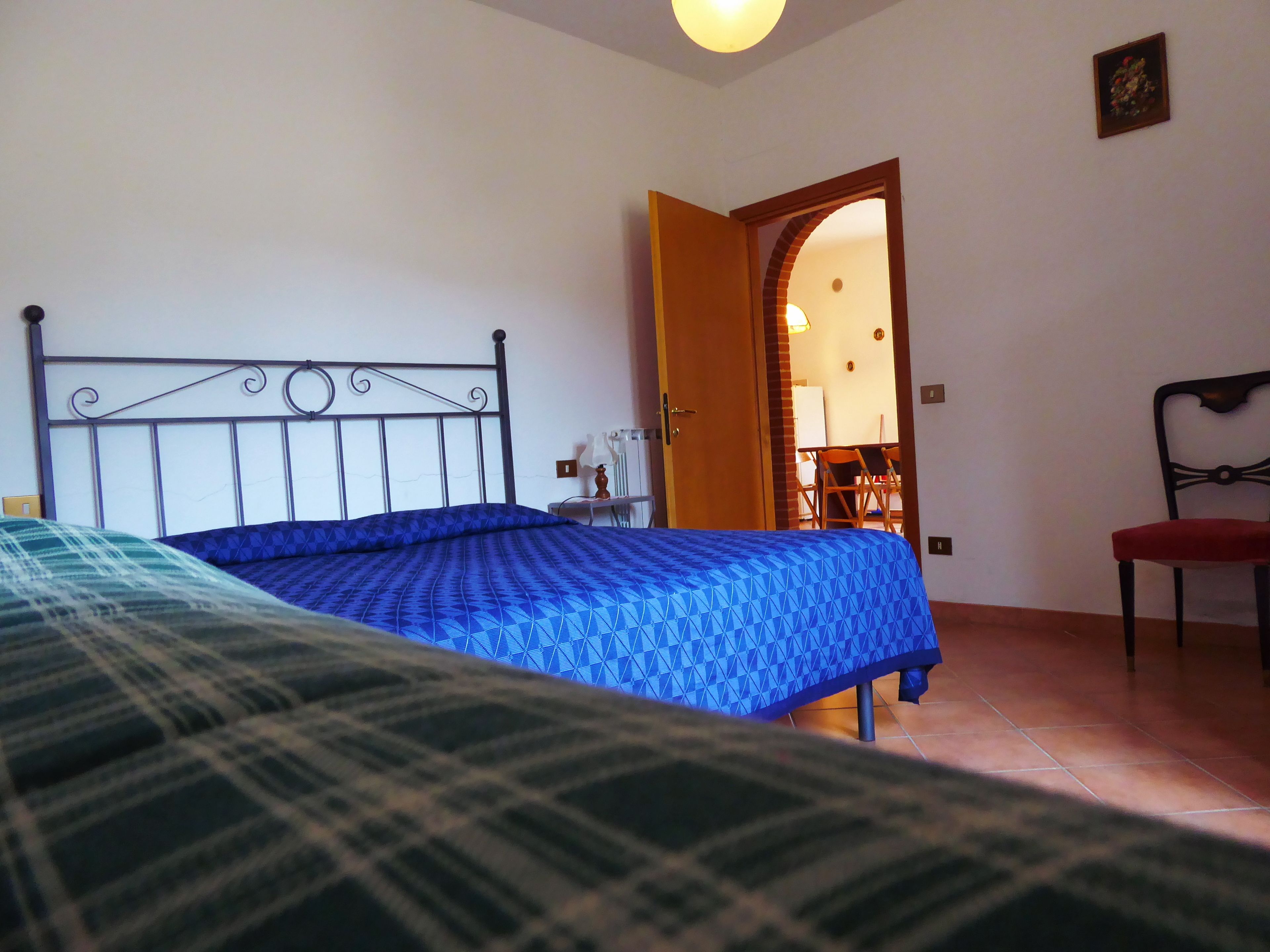 Un dormitorio con una cama, una silla y una puerta que da a otra habitación.