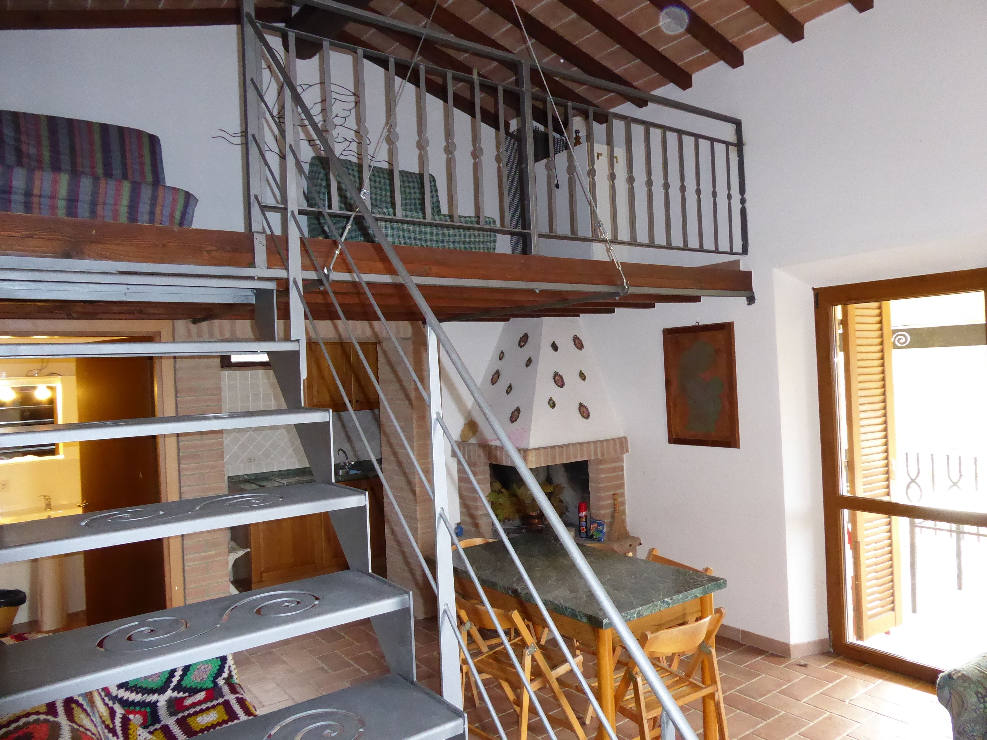 Un interior de varios niveles con una escalera, un comedor y una cocina.