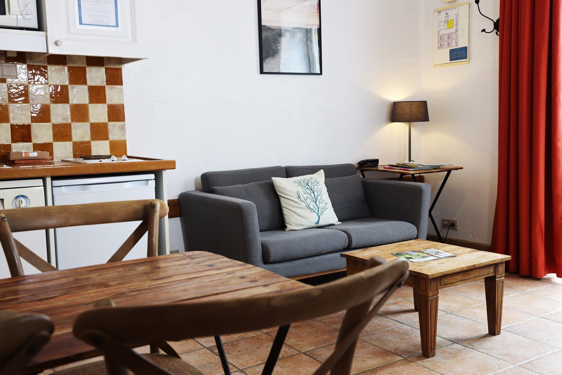 A cozy living area with a grey sofa, wooden coffee table, and a small side table with a lamp.
