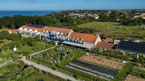 Vista aerea di una zona residenziale con case, pannelli solari e un giardino.