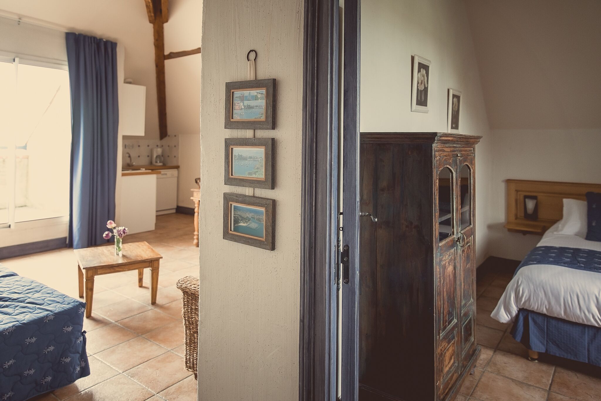 A room with a bed, a wooden cabinet, and a small table with a vase.
