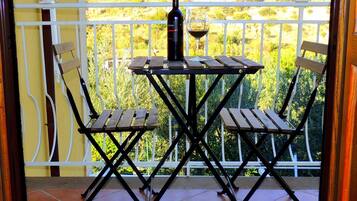 Un balcon avec une table et des chaises, une bouteille de vin et un verre.
