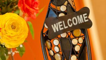 A decorative metal sculpture with a 'WELCOME' sign, surrounded by flowers.