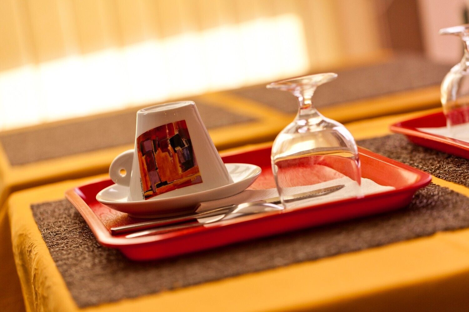 A tray with a teapot, a glass, and a spoon on a table with a textured mat.