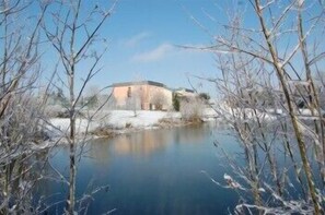 A building with a flat roof and a small pond in the foreground. - Citotel Du Circuit (Magny-Cours)