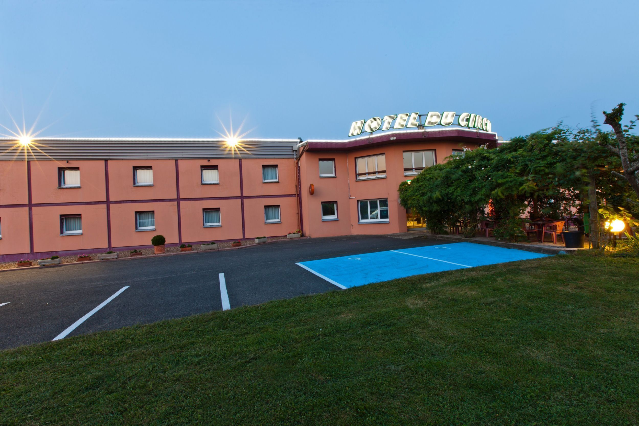 Un hotel con techo plano, varias ventanas y un estacionamiento azul.